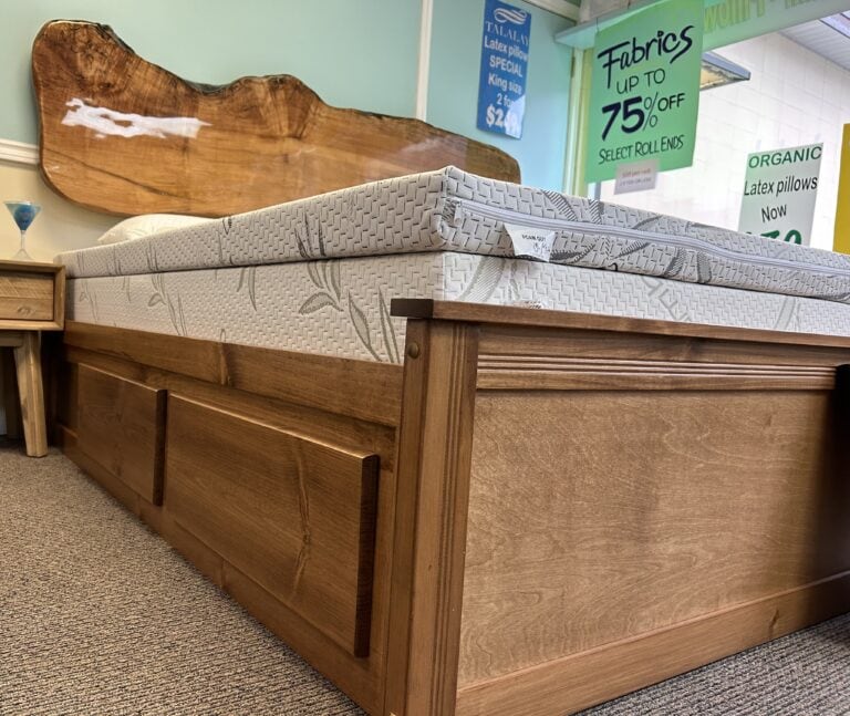 Wooden bed with mattress and sale signs.