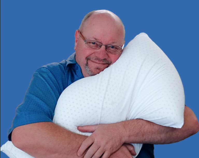 Person hugging large white pillow, smiling.
