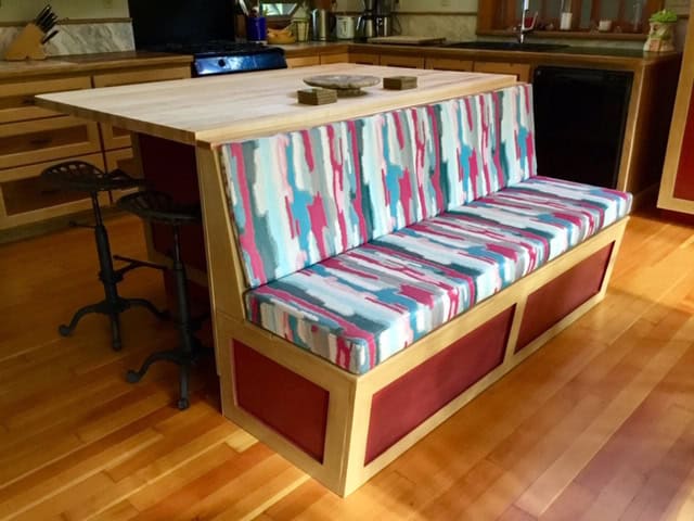 Colourful kitchen bench seating by wooden island.