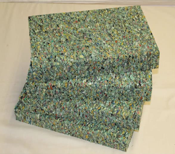 Stacked shredded paper bales on white surface.