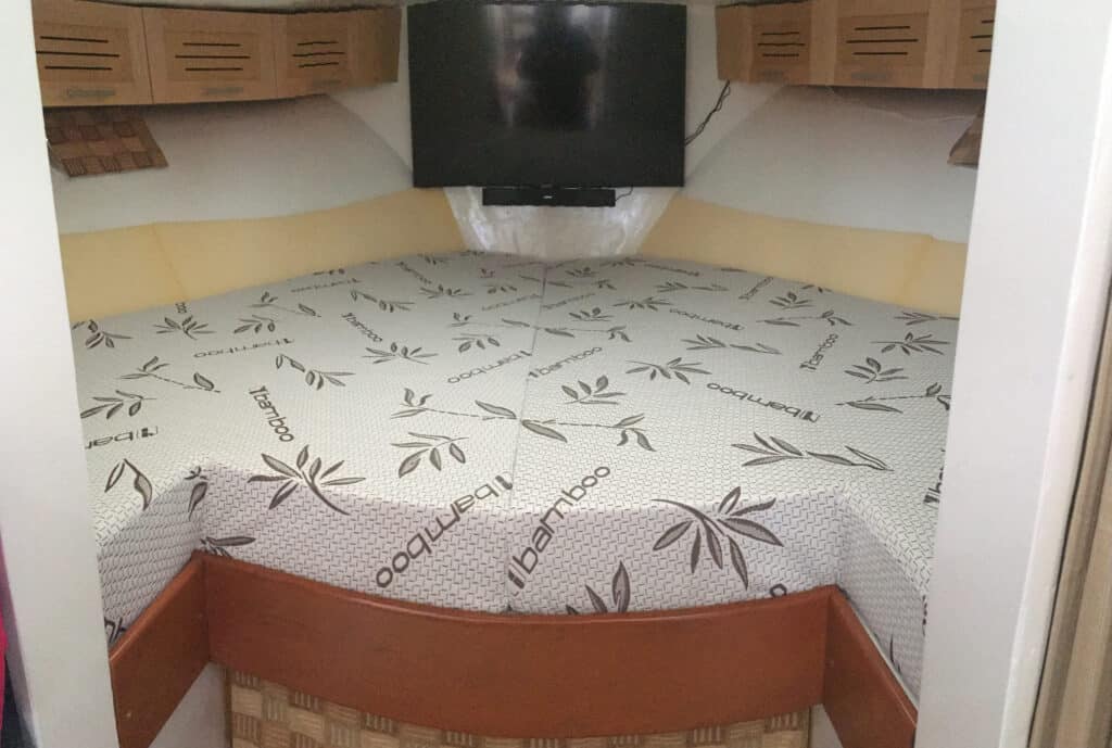 Boat cabin with bamboo-patterned mattress and TV.