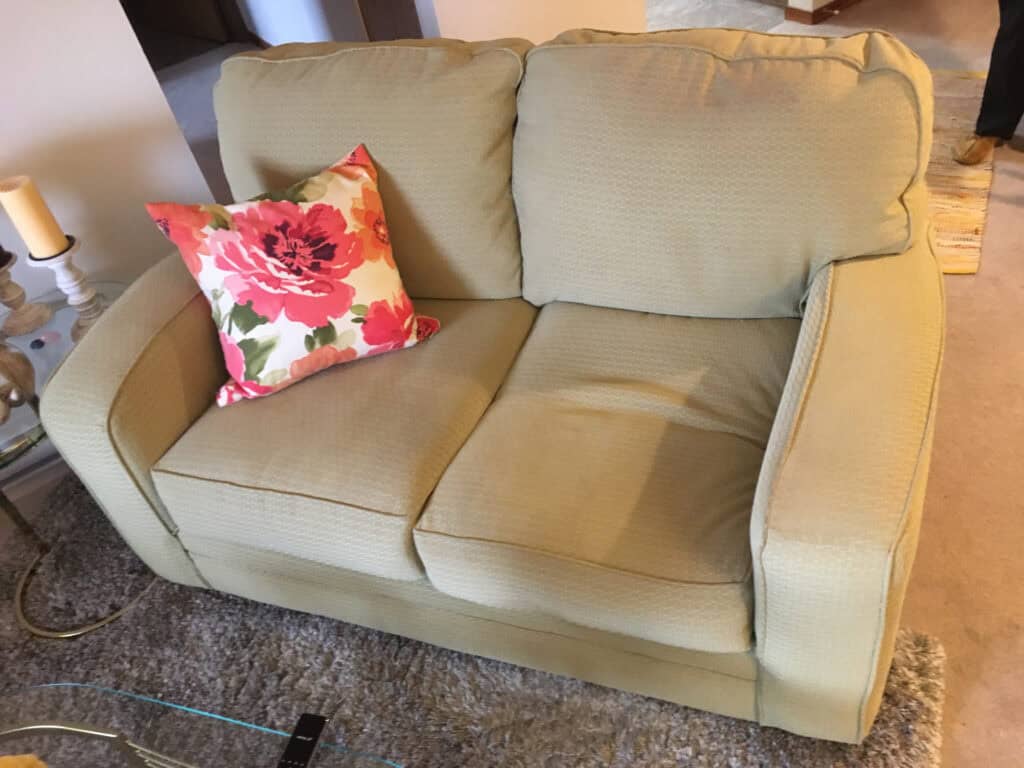 Beige loveseat with floral cushion in living room.