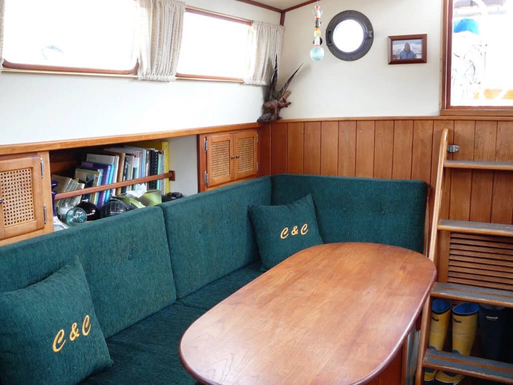 Cozy boat interior with cushions, table and bookshelves.