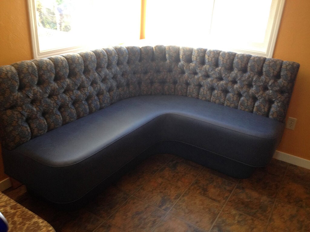 Corner tufted sofa with blue upholstery in room.