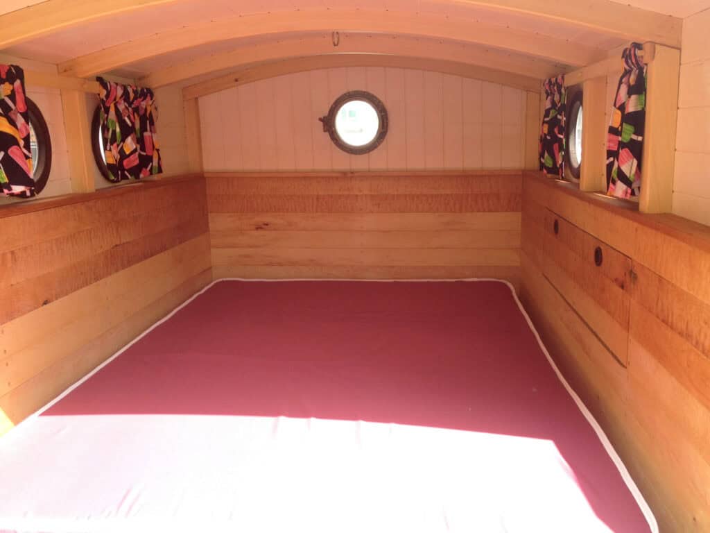 Cozy wooden camper bed with porthole windows.
