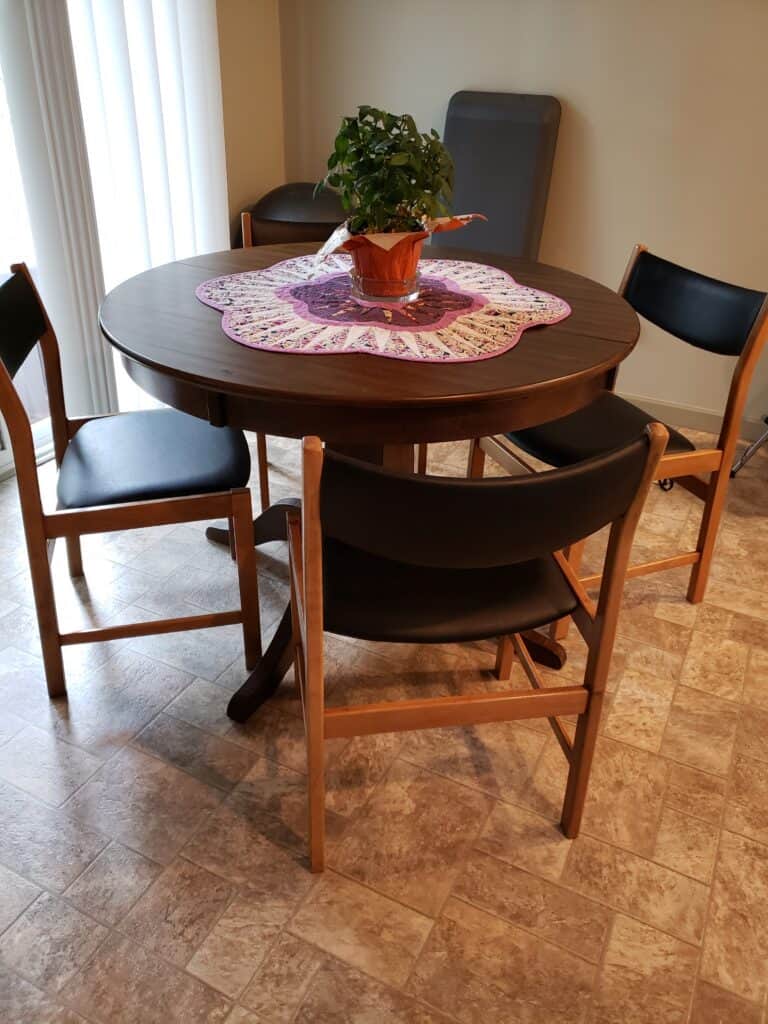 Round table with four chairs and a plant.