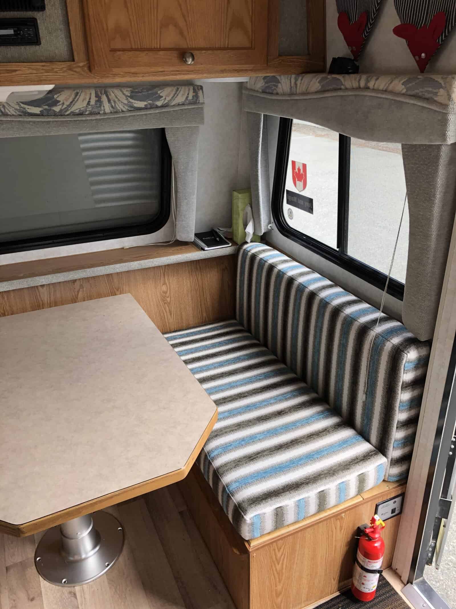 RV interior with striped seating and table.
