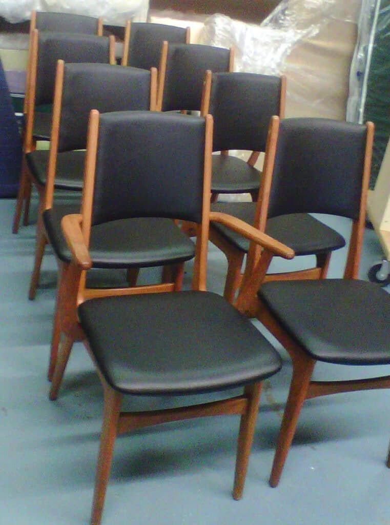 Row of wooden chairs with black cushions.