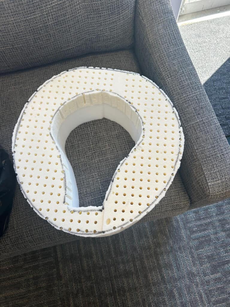 Foam cervical neck support on grey couch.