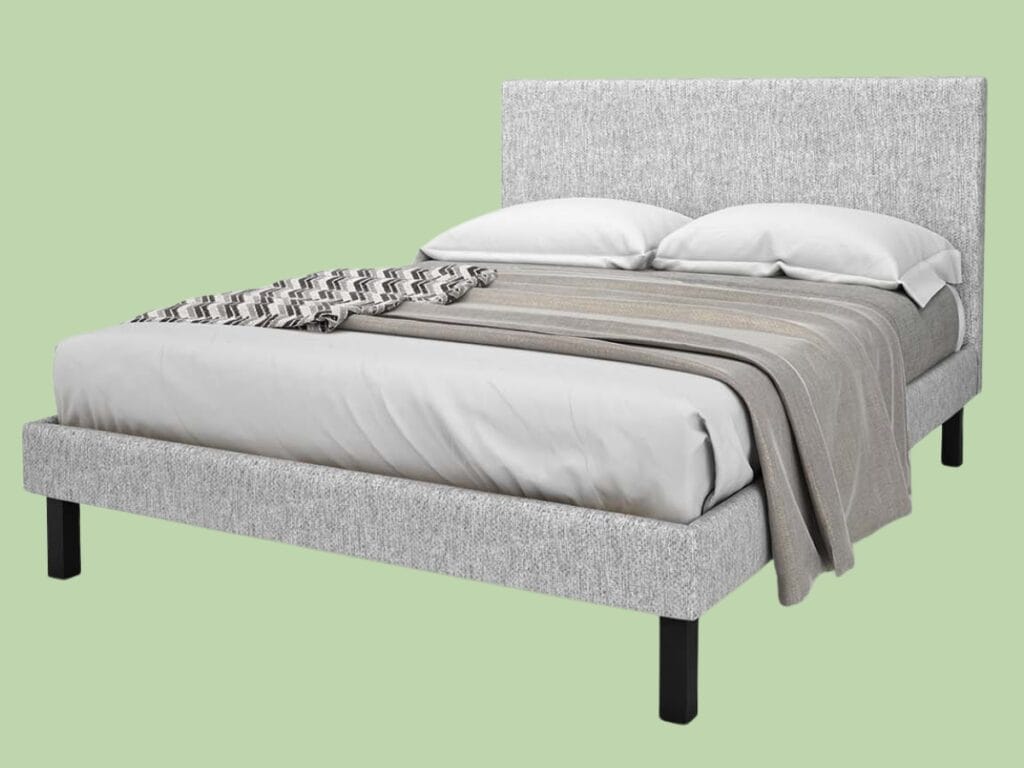 Grey upholstered bed with pillows and blanket